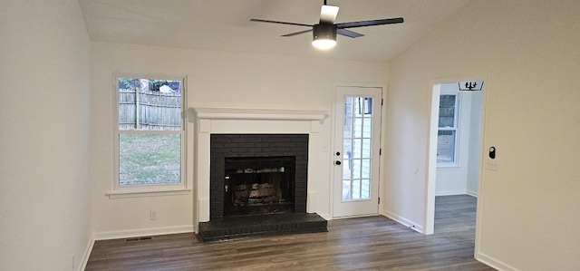 unfurnished living room featuring ceiling fan, vaulted ceiling, dark wood-type flooring, and a brick fireplace