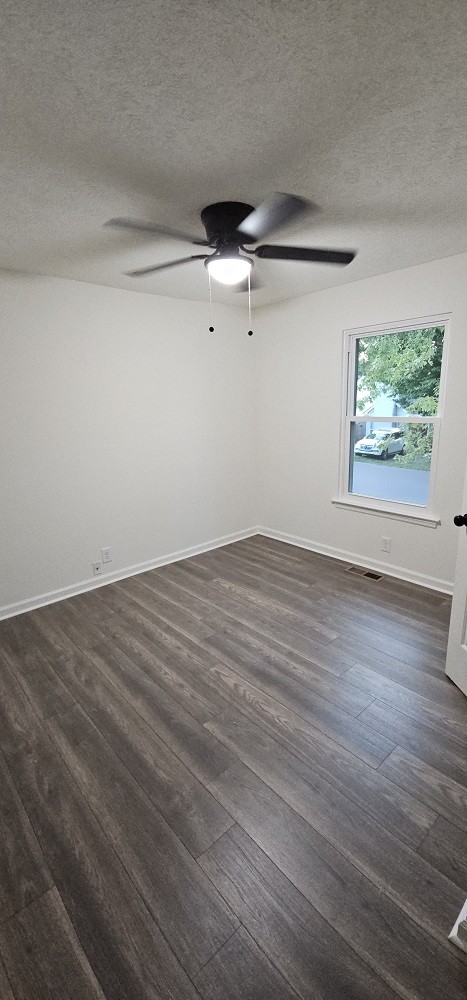 unfurnished room with dark hardwood / wood-style floors, ceiling fan, and a textured ceiling