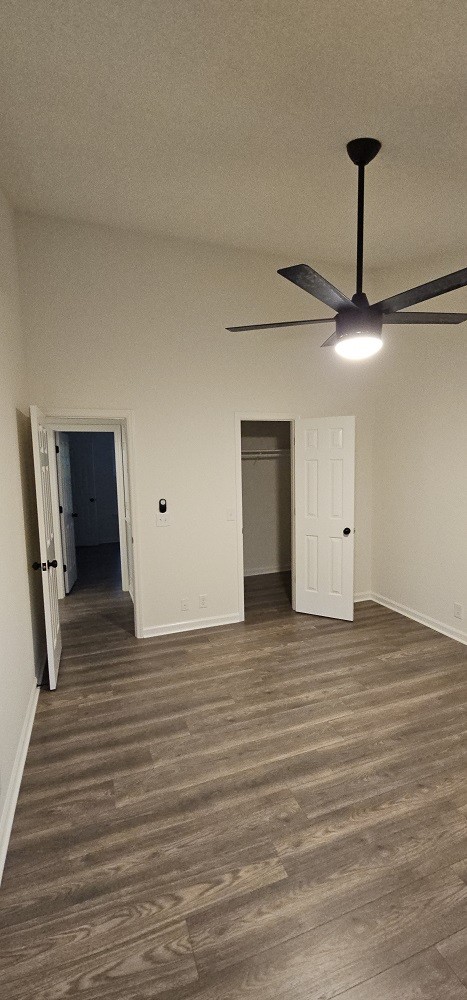 unfurnished bedroom with ceiling fan, a closet, and dark hardwood / wood-style floors