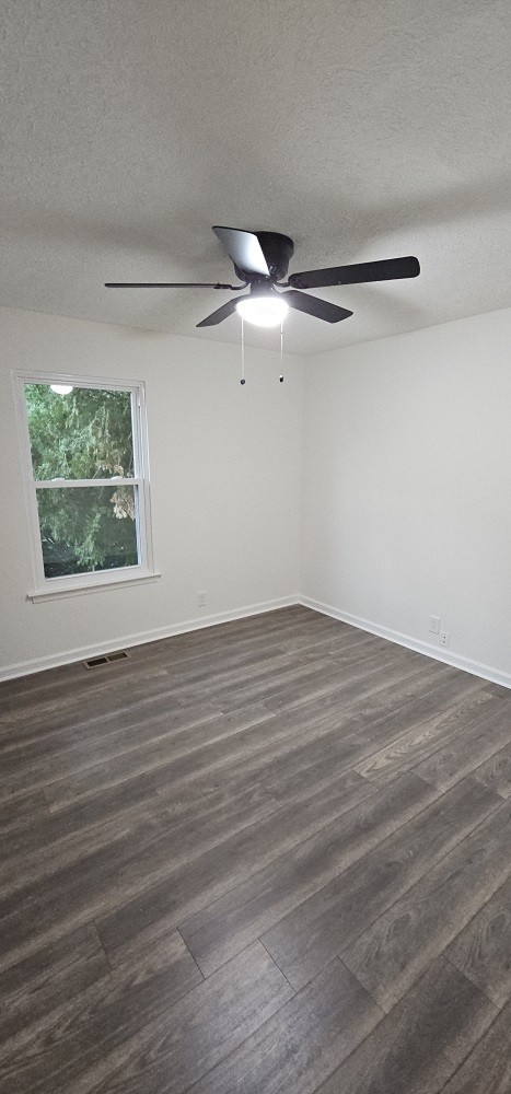 spare room with dark hardwood / wood-style floors, ceiling fan, and a textured ceiling