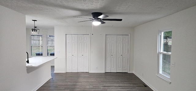 unfurnished bedroom featuring a textured ceiling, dark wood-type flooring, and ceiling fan with notable chandelier