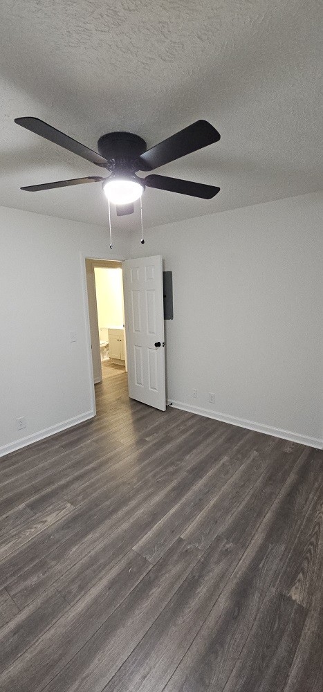 spare room with a textured ceiling, ceiling fan, and dark wood-type flooring