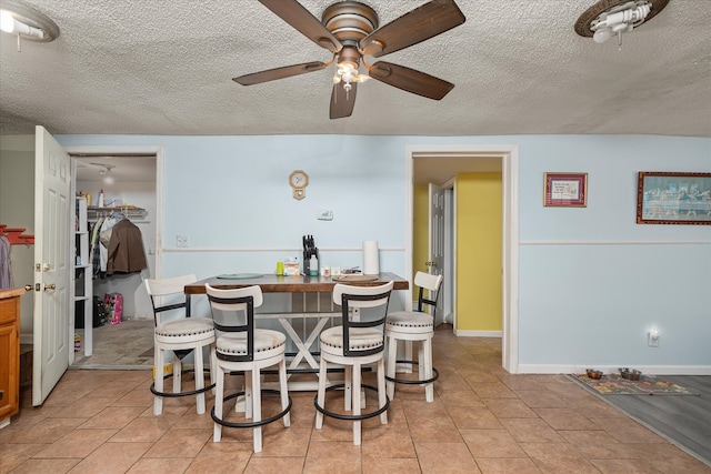 kitchen featuring a breakfast bar, ceiling fan, and a textured ceiling