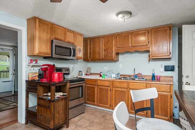 kitchen with a textured ceiling, stainless steel appliances, and sink