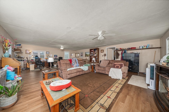 living room with ceiling fan, wood-type flooring, and a textured ceiling