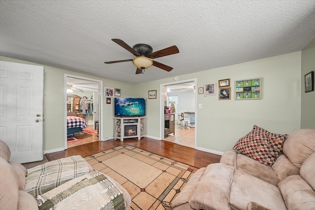 living room with ceiling fan, light hardwood / wood-style flooring, and a textured ceiling