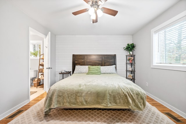 bedroom featuring ceiling fan, wooden walls, and wood-type flooring