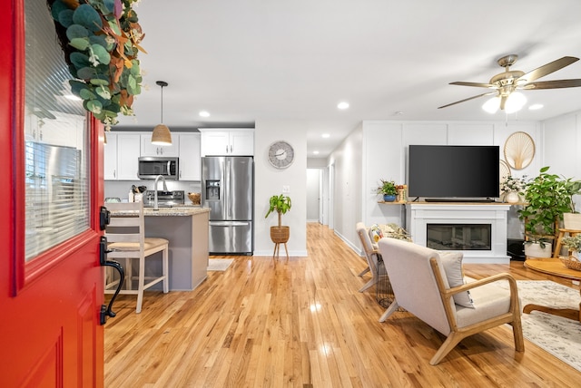 living room featuring ceiling fan and light hardwood / wood-style floors