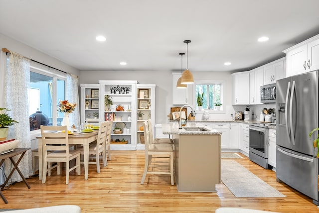 kitchen with a center island with sink, light hardwood / wood-style floors, sink, and appliances with stainless steel finishes