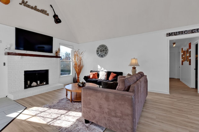 living room with light hardwood / wood-style flooring, vaulted ceiling, and a brick fireplace