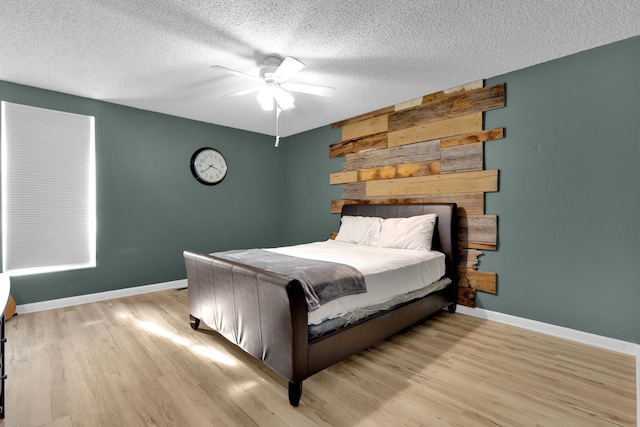 bedroom featuring ceiling fan, a textured ceiling, and light hardwood / wood-style flooring