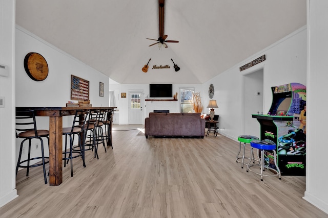 living room featuring a fireplace, light hardwood / wood-style floors, vaulted ceiling, and ceiling fan