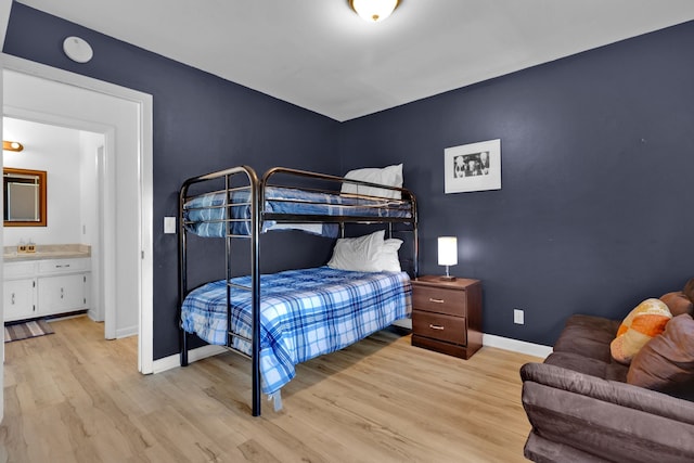 bedroom featuring connected bathroom and light hardwood / wood-style floors