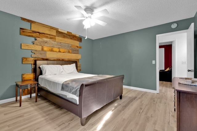 bedroom featuring ceiling fan, light hardwood / wood-style flooring, and a textured ceiling