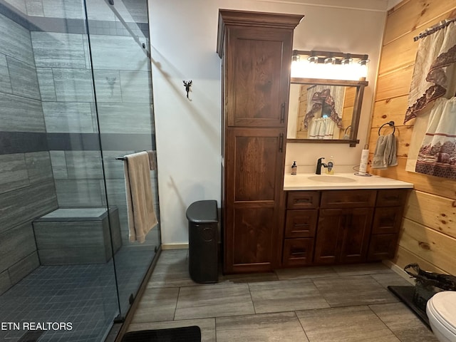 bathroom featuring wood walls, a shower with door, vanity, and toilet