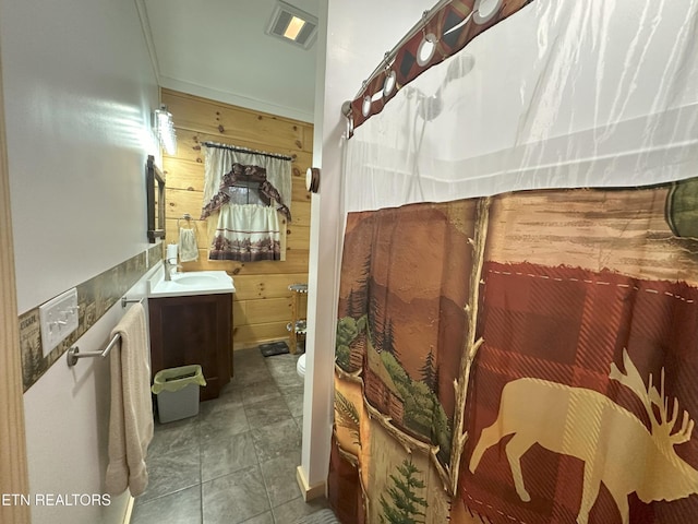 bathroom featuring vanity, toilet, and wood walls