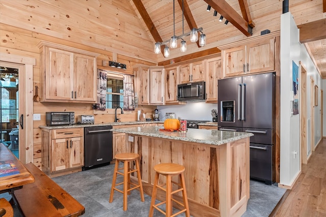 kitchen with light stone countertops, a center island, light brown cabinets, stainless steel appliances, and high vaulted ceiling