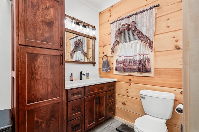 bathroom with wood walls, vanity, and toilet