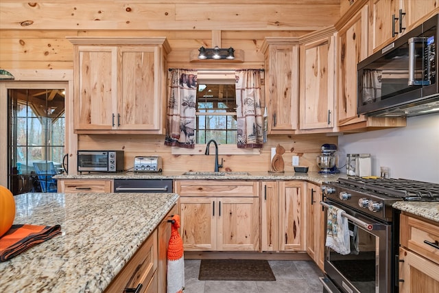 kitchen featuring plenty of natural light, light stone countertops, sink, and stainless steel stove