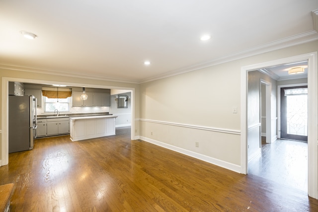 unfurnished living room with sink, dark hardwood / wood-style floors, and ornamental molding