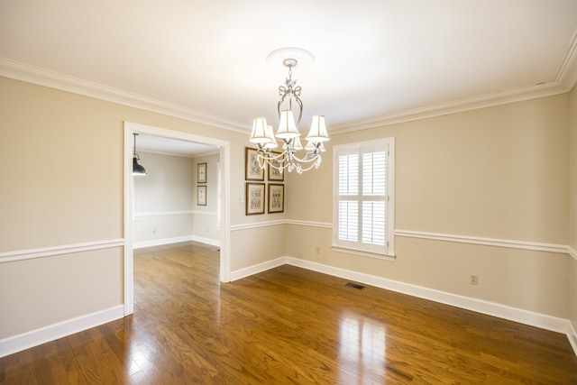 spare room featuring dark hardwood / wood-style floors, crown molding, and a chandelier