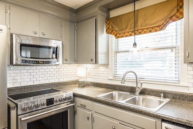 kitchen with a wealth of natural light, stainless steel appliances, decorative backsplash, sink, and gray cabinetry