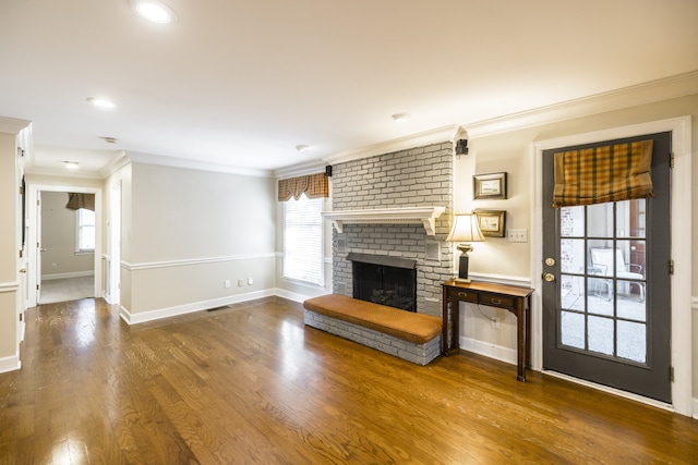 unfurnished living room with plenty of natural light, wood-type flooring, ornamental molding, and a fireplace