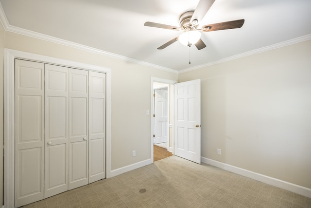 unfurnished bedroom featuring ceiling fan, crown molding, a closet, and light carpet