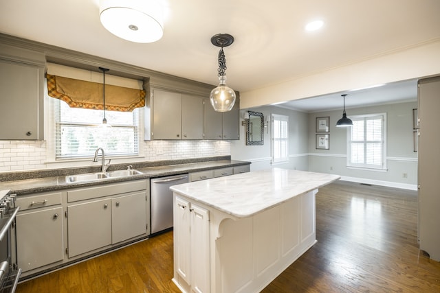 kitchen featuring decorative light fixtures, a center island, sink, stainless steel appliances, and dark hardwood / wood-style flooring