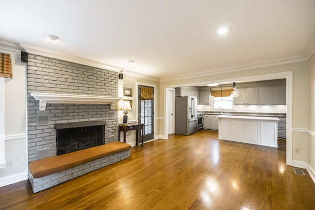 unfurnished living room featuring dark hardwood / wood-style flooring, crown molding, a fireplace, and sink