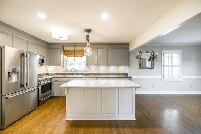 kitchen featuring premium appliances, light hardwood / wood-style floors, a center island, hanging light fixtures, and sink