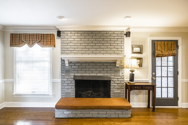 interior space featuring a brick fireplace, plenty of natural light, dark hardwood / wood-style floors, and crown molding