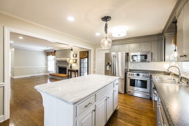 kitchen featuring a fireplace, a center island, sink, crown molding, and high quality appliances