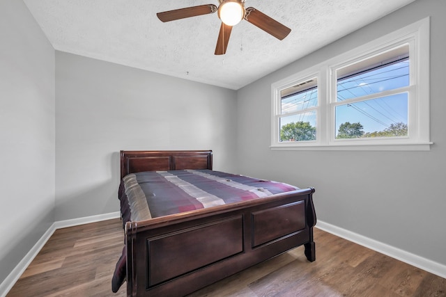 bedroom with ceiling fan, hardwood / wood-style floors, and a textured ceiling