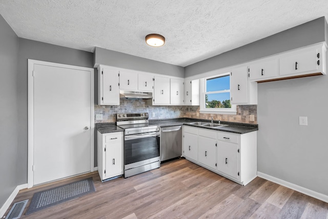 kitchen with backsplash, white cabinets, light hardwood / wood-style flooring, a textured ceiling, and appliances with stainless steel finishes