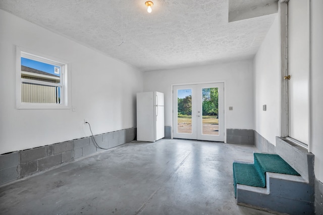 interior space featuring french doors, a textured ceiling, and concrete floors