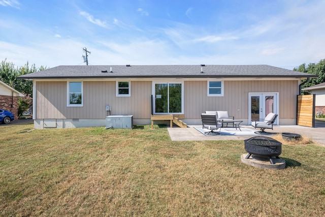 back of property with french doors, a patio, an outdoor living space with a fire pit, and a yard