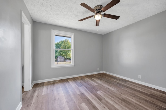 empty room with a textured ceiling, light wood-type flooring, and ceiling fan