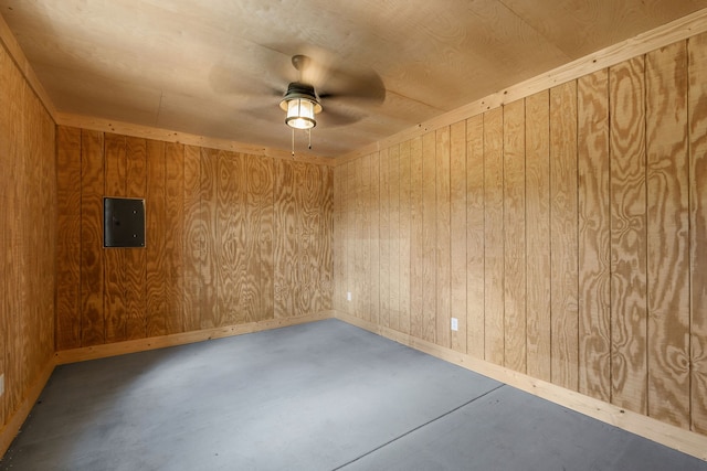 empty room featuring ceiling fan, electric panel, concrete flooring, and wooden walls