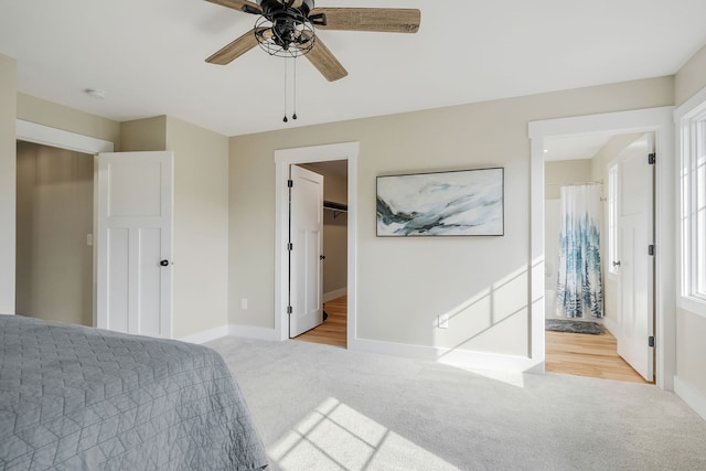 carpeted bedroom with ceiling fan, a spacious closet, ensuite bathroom, and a closet