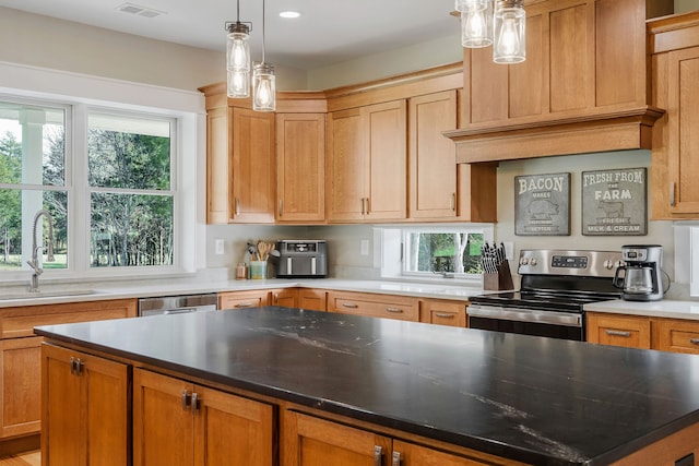 kitchen featuring sink, a center island, decorative light fixtures, and appliances with stainless steel finishes