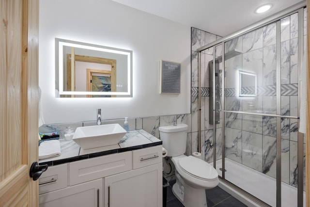 bathroom featuring vanity, tile patterned flooring, toilet, tile walls, and a shower with shower door