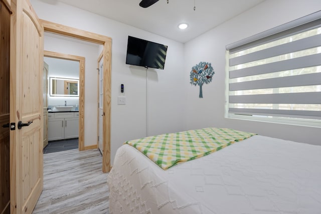 bedroom with light wood-type flooring, ensuite bathroom, ceiling fan, and sink