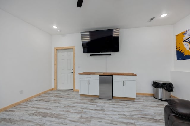 bar featuring butcher block countertops, stainless steel refrigerator, white cabinets, and light wood-type flooring