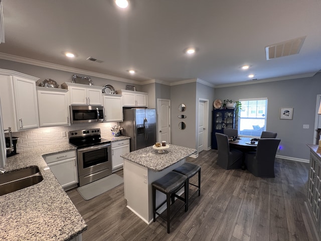 kitchen featuring light stone counters, stainless steel appliances, a center island, and white cabinets