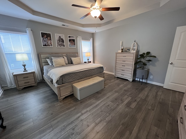 bedroom featuring dark wood-type flooring, ceiling fan, and a tray ceiling