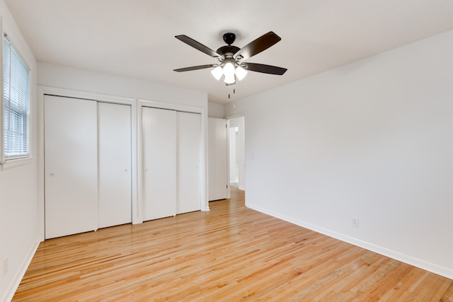 unfurnished bedroom featuring ceiling fan, light hardwood / wood-style floors, and multiple closets