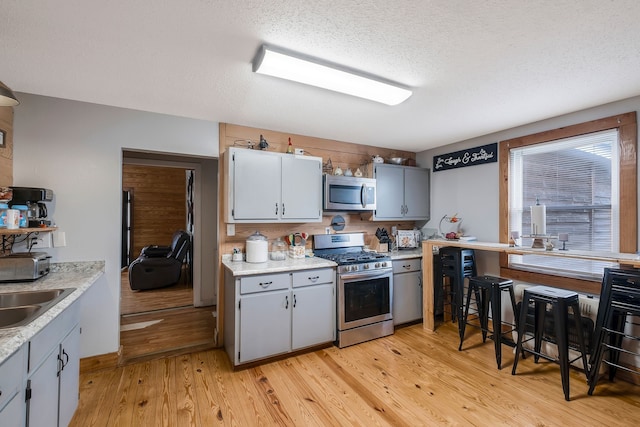 kitchen featuring appliances with stainless steel finishes, light wood-type flooring, a textured ceiling, and sink