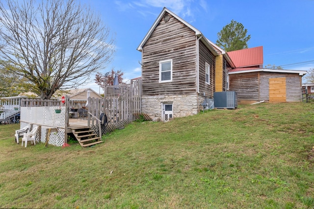 view of side of property featuring a lawn, a wooden deck, and central AC