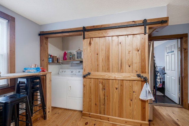 washroom featuring light wood-type flooring, washing machine and dryer, and a barn door